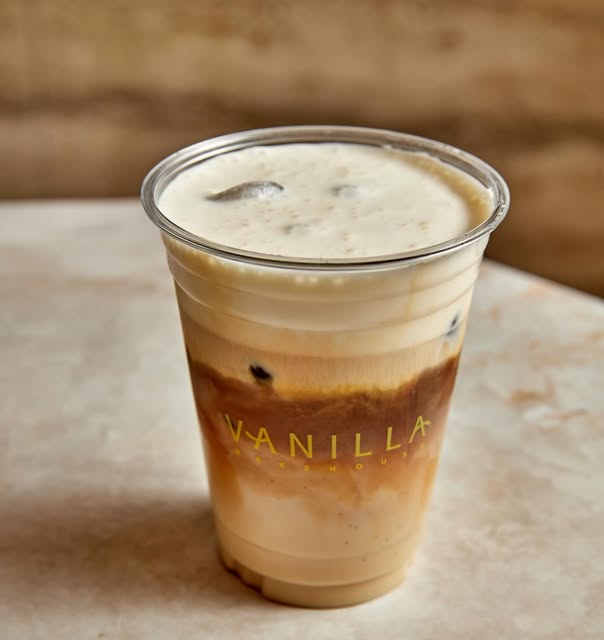 Barista pouring latte art beside fresh pastries